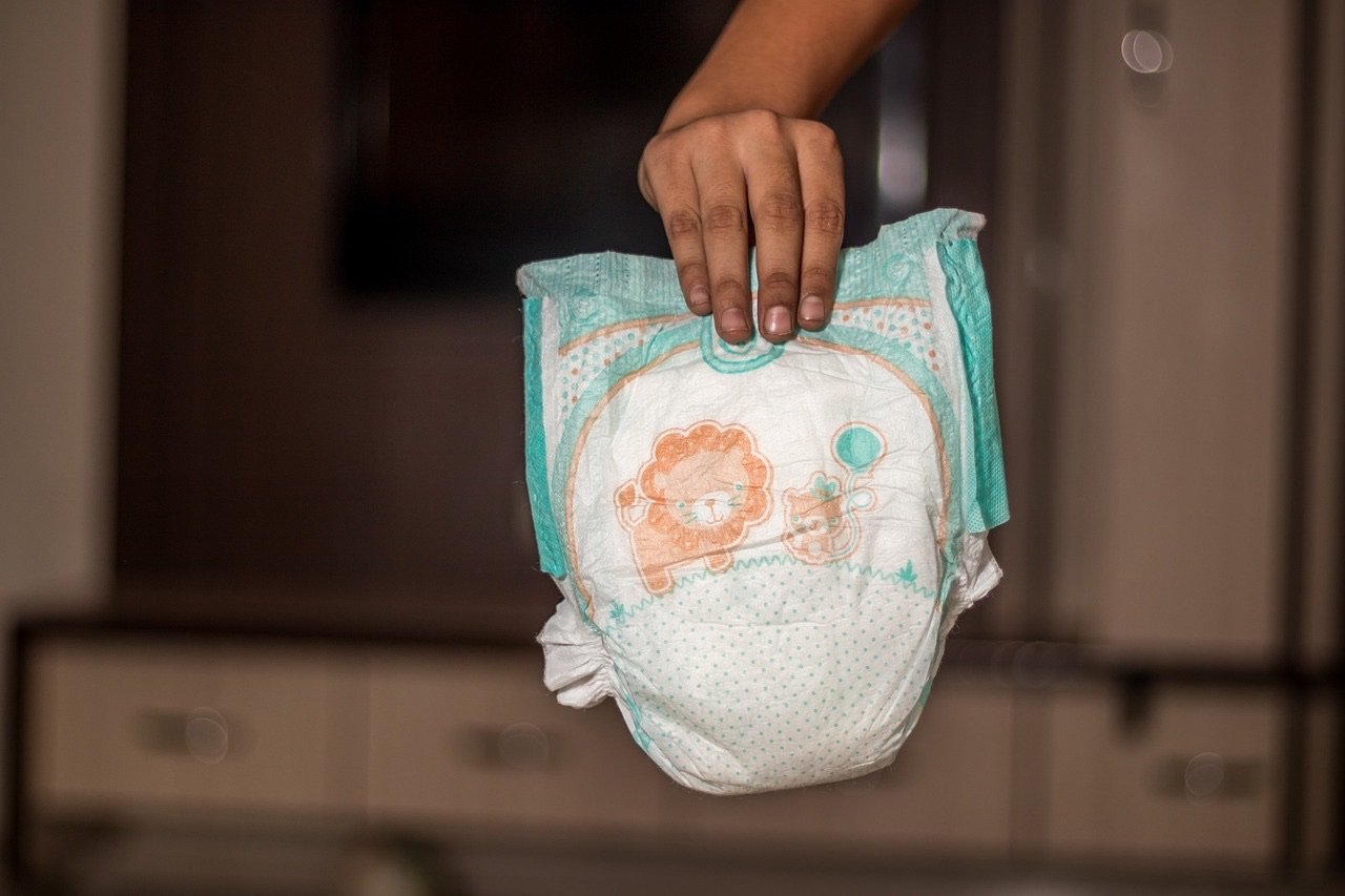 A teen mom holding a diaper.